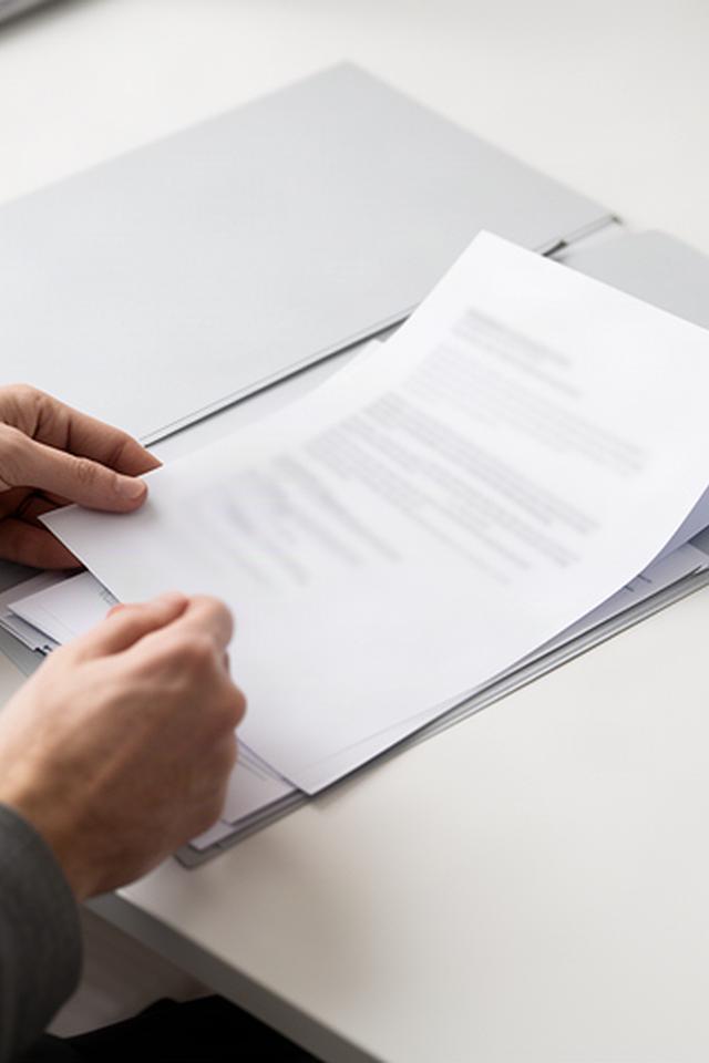 Personal documents being sorted into a labelled folder on a clear desk